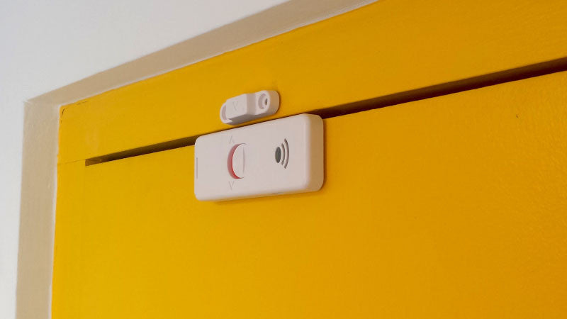 Closed yellow door with a door sensor securely attached