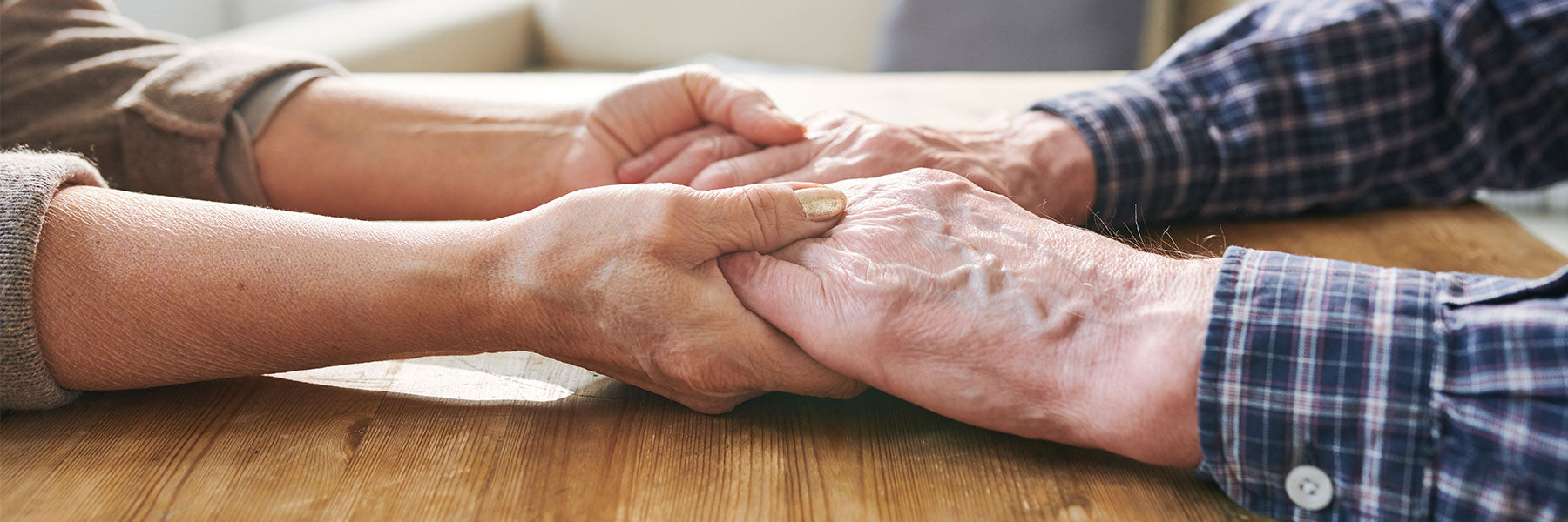 Two elderly people holding hands over a table