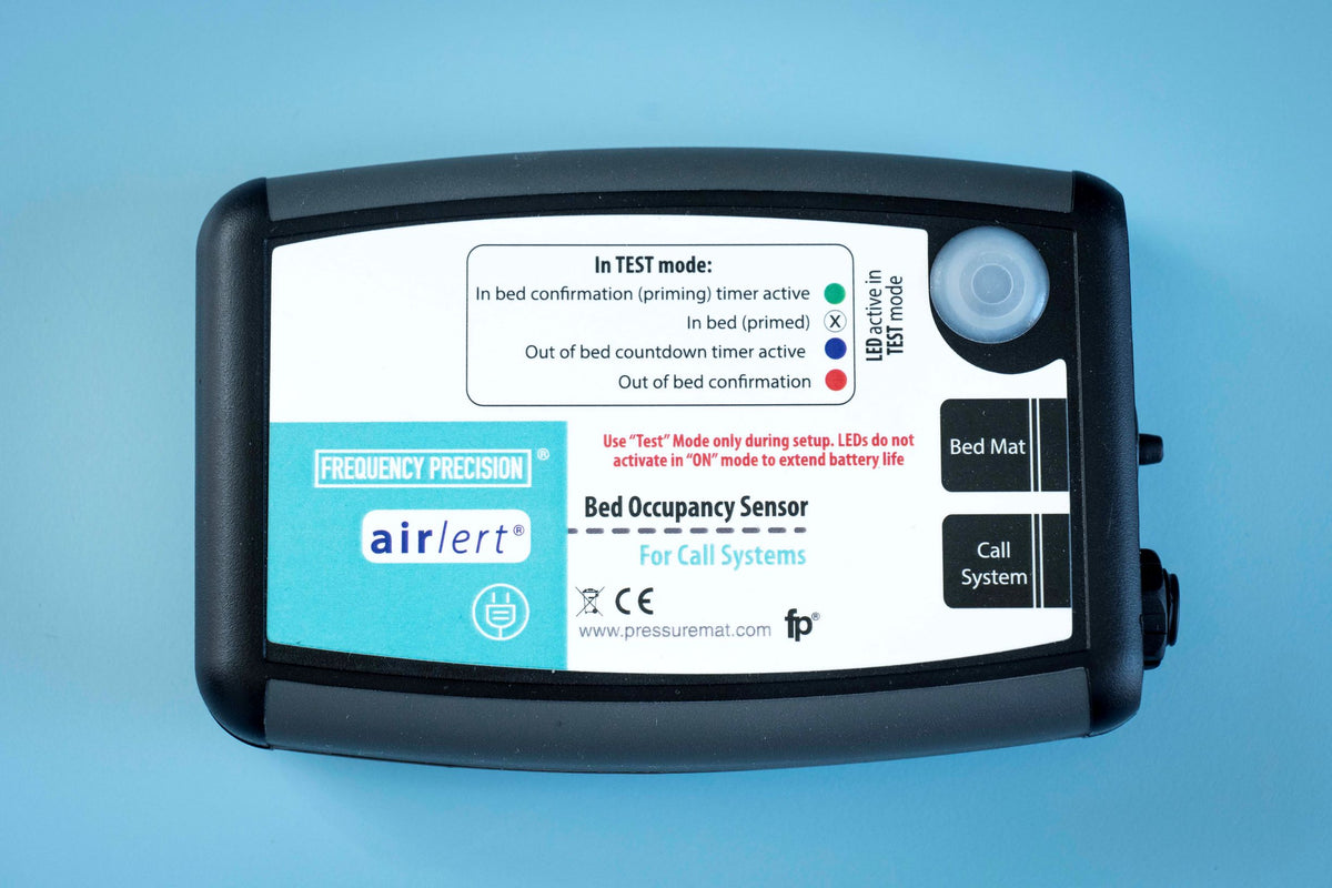 Photo of a bed occupancy sensor set against a blue background
