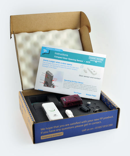 Box containing a door sensor and bleeper pager set, with an open piece of paper displaying instructions