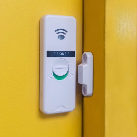 Wall-mounted wireless door sensor activated against a yellow backdrop