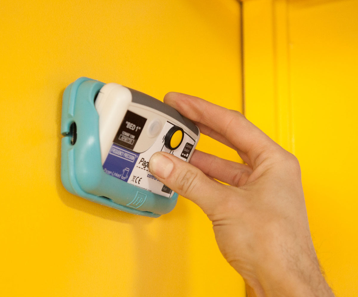 Control box being placed inside protective rubber case, attached to a yellow wall