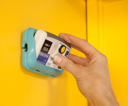 Control box being placed inside protective rubber case, attached to a yellow wall
